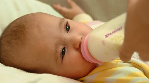 Маленька новонароджена дитина п'є молоко з пляшки — стокове фото