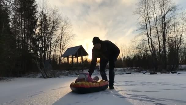 Tata popycha córki na gumowej rurki nadmuchiwane śnieg — Wideo stockowe