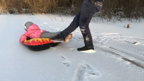 Pappa driver hennes dotter på en gummi uppblåsbara snow tube — Stockvideo