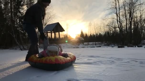 Tata popycha córki na gumowej rurki nadmuchiwane śnieg — Wideo stockowe