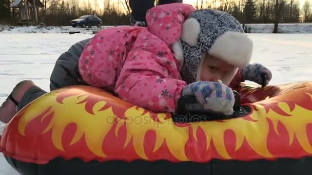 Маленькая девочка и резиновая надувная снежная трубка — стоковое видео