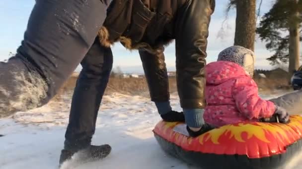 Pappa driver hennes dotter på en gummi uppblåsbara snow tube — Stockvideo