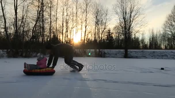 Apa lánya megnyomja egy felfújható hó gumicső — Stock videók