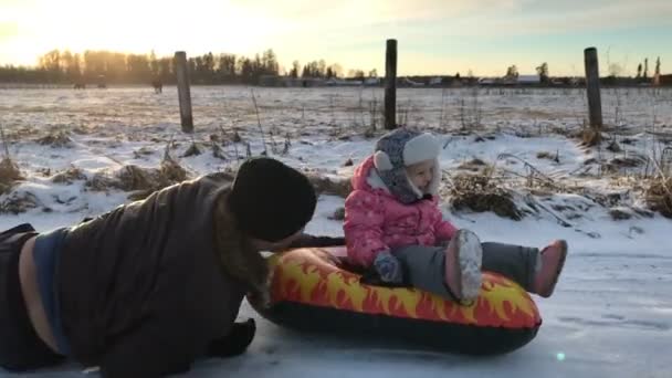 Tata popycha córki na gumowej rurki nadmuchiwane śnieg — Wideo stockowe