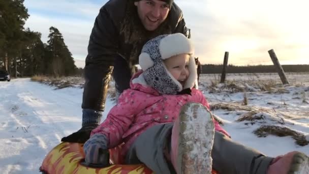 Papa schiebt ihre Tochter auf einen aufblasbaren Gummischlauch — Stockvideo