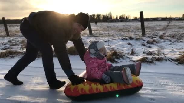 Apa lánya megnyomja egy felfújható hó gumicső — Stock videók