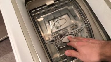 adam dikey bir çamaşır makinesi kapıyı açar ve Çamaşırhane çeker.