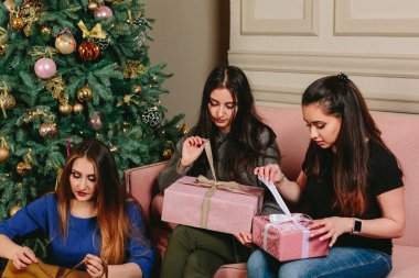 Üç güzel genç kız hediyeler Noel ağacı yakınındaki açmak. Stüdyo yatay dikey.