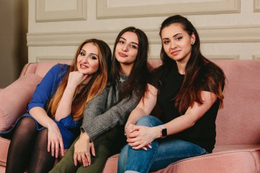 Üç güzel genç kız kanepe üzerinde Noel ağacının yakınında. Stüdyo yatay dikey.