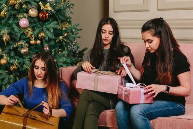 Üç güzel genç kız hediyeler Noel ağacı yakınındaki açmak. Stüdyo yatay dikey.