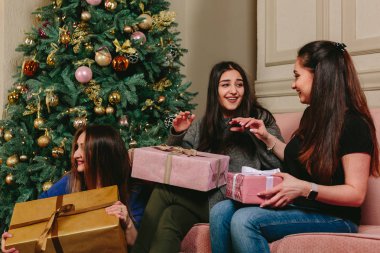 Üç güzel genç kız hediyeler Noel ağacı yakınındaki açmak. Stüdyo yatay dikey.