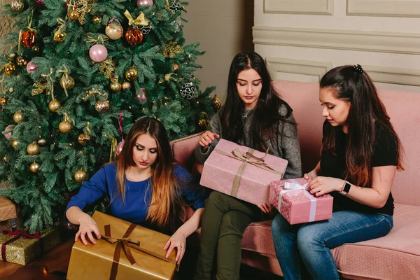 Üç güzel genç kız hediyeler Noel ağacı yakınındaki açmak. Stüdyo yatay dikey.