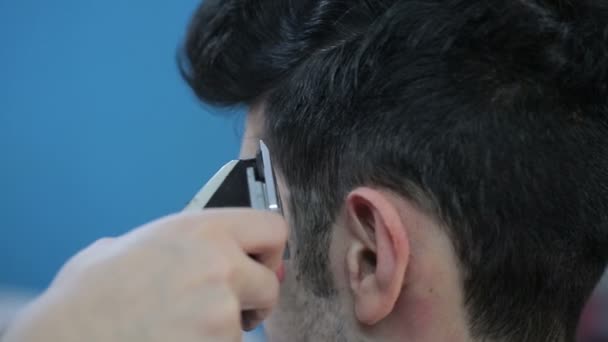 Barber coupe les cheveux du client avec une tondeuse . — Video