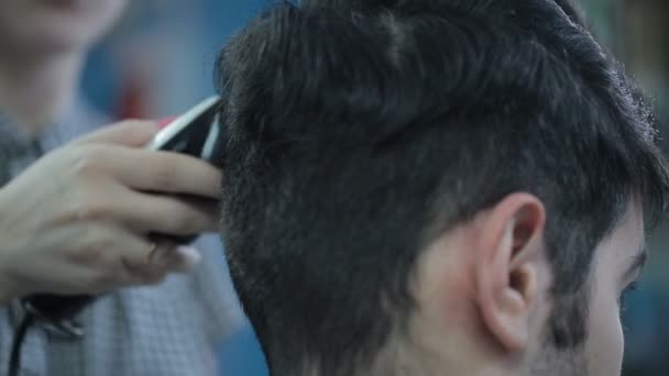 Kapper snijdt de haren van de client met clipper. — Stockvideo