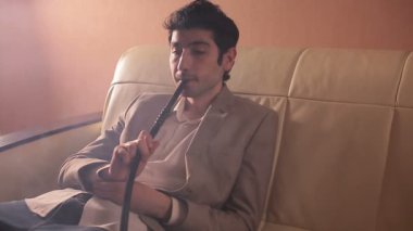 Bir nargile sigara ve rahat Oda bir kanepe üzerinde rahatlatıcı bir işadamı.