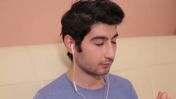Молодой человек в наушниках слушает музыку в комнате . — стоковое видео