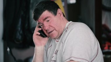 Sakallı yetişkin adam telefonda konuşuyor.