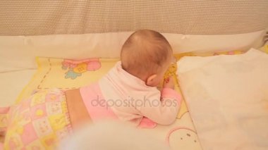 Şirin Bebek beşiğinde bir emzik ile oynarken.