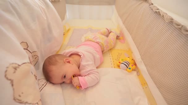 Милая малышка, играющая с пустышкой в кроватке . — стоковое видео