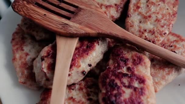 Vele schnitzels op een plaat en de houten mixers draaien rond hun as. — Stockvideo