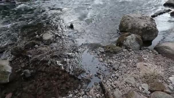 Κάμερα κινείται από δεξιά προς τα αριστερά και πυροβολεί ως τον ποταμό σκουπίσματα πέτρες στην πορεία. — Αρχείο Βίντεο
