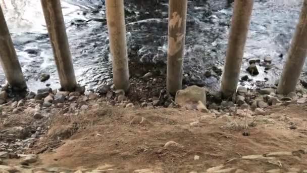 Déplacement de la rivière sous le pont au début du printemps pendant la journée. Vidéo vue de côté . — Video