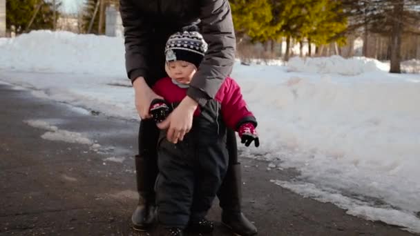 Mamma och hennes lilla barn på gatan i vintern på dagtid. — Stockvideo