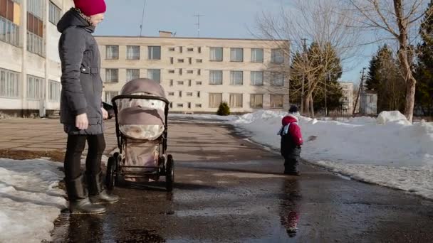 Μαμά και το μικρό παιδί στον δρόμο το χειμώνα στη διάρκεια της ημέρας. — Αρχείο Βίντεο