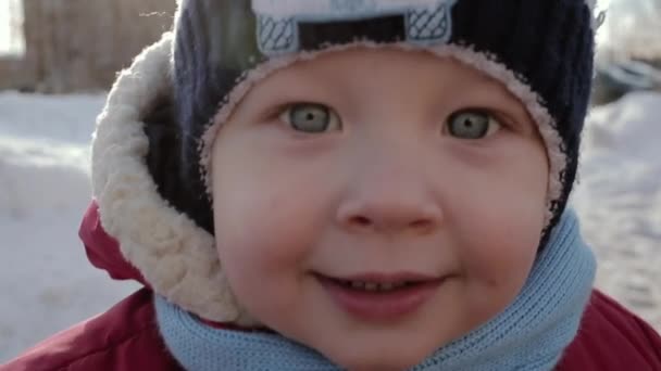 Kleines Kind mit ausdrucksstarken Augen blickt in die Kamera und lächelt. — Stockvideo