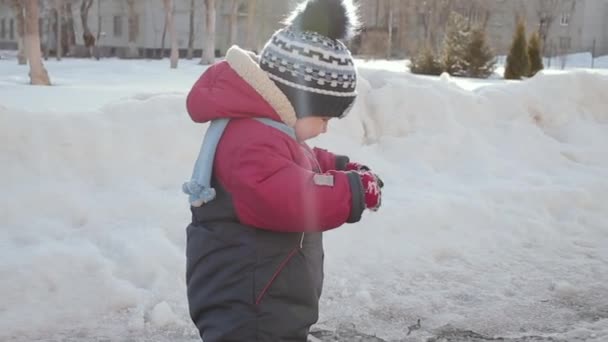 Kleine jongen spelen met sneeuw op zijn handschoenen. — Stockvideo