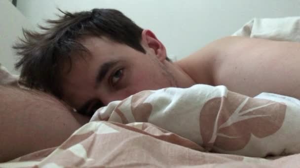 Ten leží v posteli ráno po probuzení a otevře oči. — Stock video
