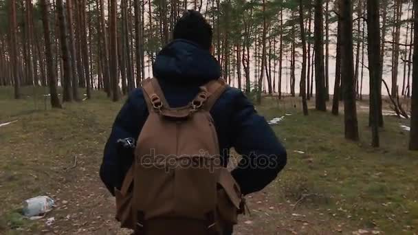 Камера преследует человека и убегает, когда он идет с рюкзаком в лесу . — стоковое видео