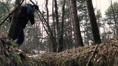 Adam bir sırt çantası ile bir hendek atlar.