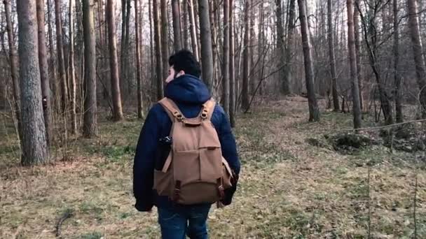 Camera chases the person and takes off as he walks with a backpack in the forest. — Stock Video