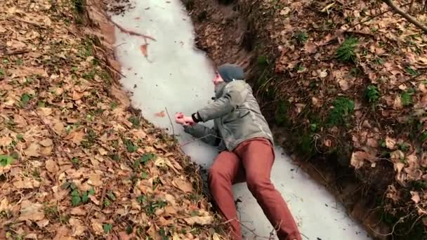 La caméra tourne comme un homme se lève qui a glissé sur la glace dans la forêt . — Video