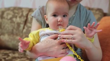 Anne çocuk onun ellerinde tutan ve onu bir emzik verir.