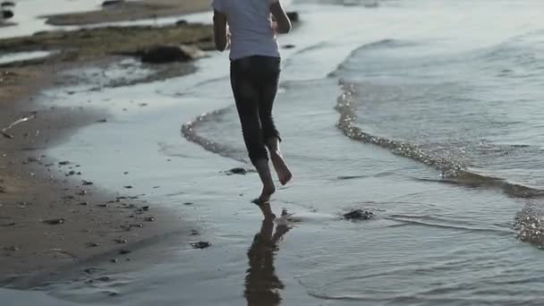 Chica joven corre a lo largo de la playa en cámara lenta — Vídeo de stock