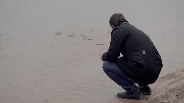 El hombre está triste en la orilla del mar en el otoño — Vídeos de Stock