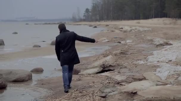 Hombre camina a lo largo de la orilla del mar en el otoño — Vídeo de stock