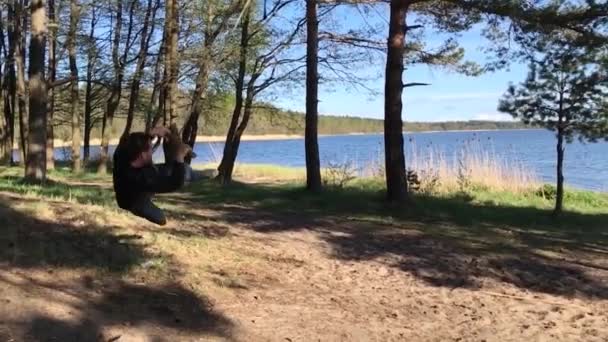 Man swingen op een geïmproviseerde schommel op een boom. boom rope swing stok — Stockvideo