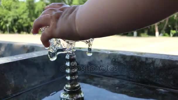 Маленький ребенок играет с питьевым фонтаном — стоковое видео
