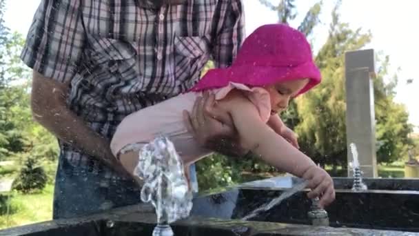 Маленький ребенок играет с питьевым фонтаном в замедленной съемке — стоковое видео