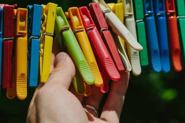 Grupo de pinzas de ropa de colores que un hombre sostiene . — Foto de Stock