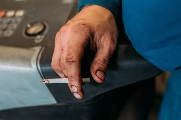 Mão suja de um mecânico guarda um cigarro . — Fotografia de Stock