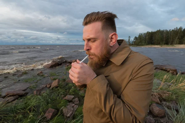 Fırtınalı havalarda sahil üzerinde bir sigara ile sakallı adam