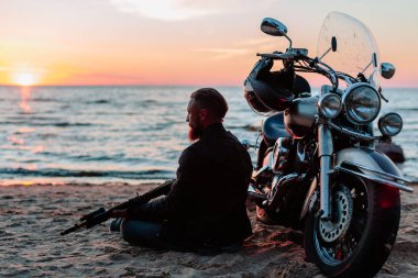 gün batımında sahilde Bisiklet yakınındaki otomatik silahlarla motorcu