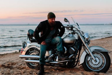 Gün batımında sahilde bir motorcu.