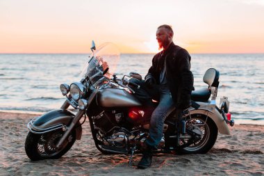 Gün batımında sahilde bir motorcu.