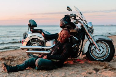 Gün batımında sahilde onun motosiklet yakınındaki motorcu aittir