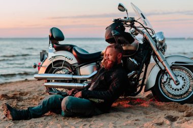 Gün batımında sahilde onun motosiklet yakınındaki motorcu aittir
